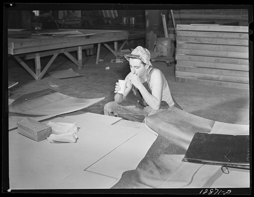 New York, New York. Preparing the defense bond sales photomural, designed by the Farm Security Administration, to be installed in the Grand Central terminal, in the shop of a contractor. Workman eating his lunch