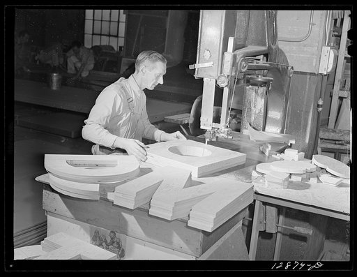 New York, New York. Preparing the defense bond sales photomural, designed by the Farm Security Administration, to be installed in the Grand Central terminal, in the shop of a contractor. Cutting out plywood letters used for the text
