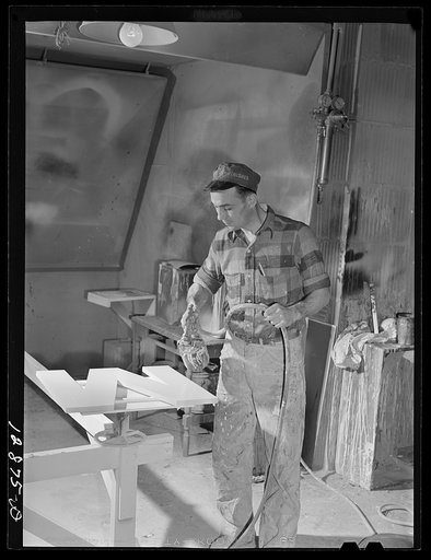 New York, New York. Preparing the defense bond sales photomural, designed by the Farm Security Administration, to be installed in the Grand Central terminal, in the shop of a contractor. Spray painting cutout plywood letters used for the text