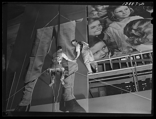 New York, New York. Installing the defense bond sales photomural, prepared by the Farm Security Administration, in the concourse of the Grand Central terminal. Erecting a mounted section of one of the large figures