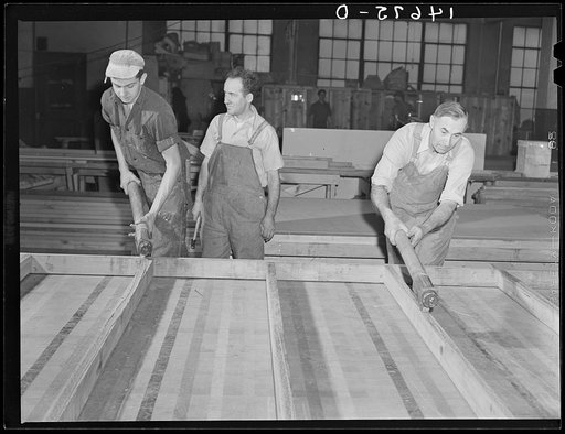New York, New York. Preparing the defense bond sales photomural, designed by the Farm Security Administration, to be installed in the Grand Central terminal, in the shop of a contractor. Applying glue to a frame which is to hold one of the sections mounted on homosote