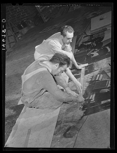 New York, New York. Preparing the defense bond sales photomural, designed by the Farm Security Administration, to be installed in the Grand Central terminal, in the shop of a contractor. Stripping out overlaps during the mounting of a section