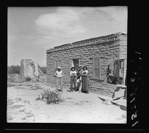 Father and son before their house. Two girls from a neighboring house pose with them. "Those two girls are 'too old' to go to school, so they just play around with my boy." (Girls' ages, fourteen and sixteen; the older one has only one good eye). Hudson, Colorado