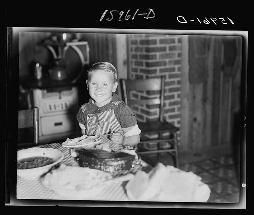 Child of former sharecropper eating at table. Southeast Missouri Farms. This is the same boy shown in negative 31215-D, two years later