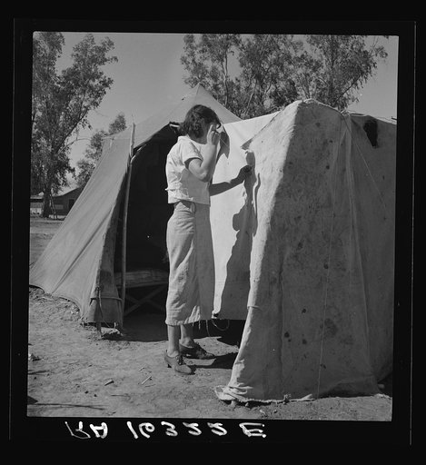 Woman in a California pea pickers' camp, mending the tent