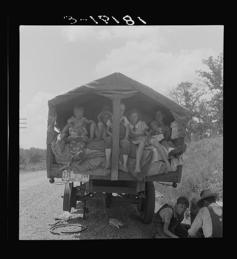 On highway no. 1 of the "OK" state near Webbers Falls, Muskogee County, Oklahoma. Seven children and eldest son's family. Father was a blacksmith in Paris, Arkansas. Son was a tenant farmer. "We're bound for Kingfisher (Oklahoma wheat) and Lubbock (Texas cotton). We're not trying to but we'll be in 