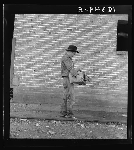 Cotton picker during strike carrying his Farm Security Administration grant of food and necessities from warehouse to Farm Security Administration Shafter camp for migrants, where he lives with his family. Bakersfield, California