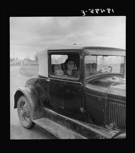 During the cotton strike, the father, a striking picker, has left his wife and child in the car while he applies to the Farm Security Administration for an emergency food grant. Shafter, California