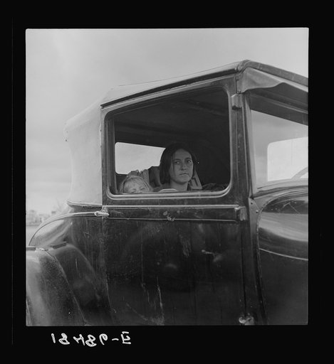 During the cotton strike, the father, a striking picker, has left his wife and child in the car while he applies to the Farm Security Administration for an emergency food grant. Shafter, California