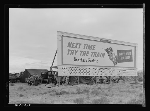 Untitled photo, possibly related to: Three families camped on the plains along U.S. 99 in California. They are camped behind a billboard which serves as a partial windbreak. All are in need of work
