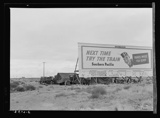 Untitled photo, possibly related to: Three families camped on the plains along U.S. 99 in California. They are camped behind a billboard which serves as a partial windbreak. All are in need of work