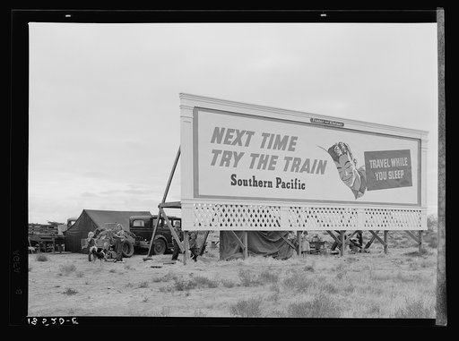 Untitled photo, possibly related to: Three families camped on the plains along U.S. 99 in California. They are camped behind a billboard which serves as a partial windbreak. All are in need of work