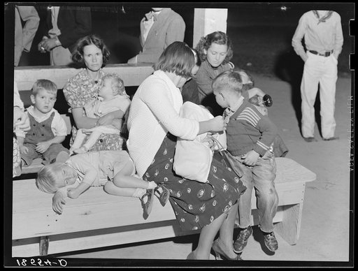 Tired mothers and tired children at the end of the Halloween party at Shafter migrant camp, California