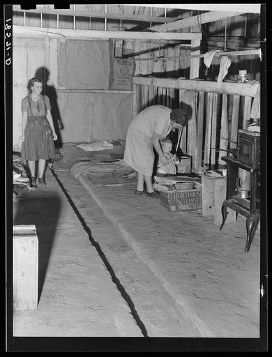 Living conditions of workers in agriculture on whom depend the crops of California. Family of migratory cotton pickers, originally from Oklahoma, living in abandoned cow barn. Note bed in corner. Kern County, California