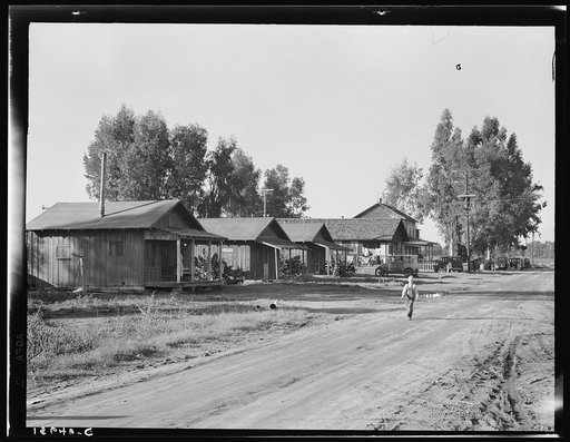 Early stage in the history of the farm experiment on the old Mineral King Ranch. These old buildings in which the ten cooperating families now live will be replaced by modern separate homes. Tulare County, California