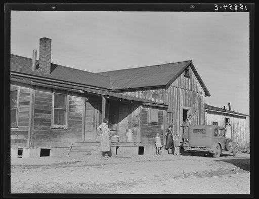 Outskirts of Firebaugh, west side of San Joaquin Valley, California. Six families with twenty-two children live in this house. Cotton workers. "He's good (the boss) he lets us live here without paying rent"