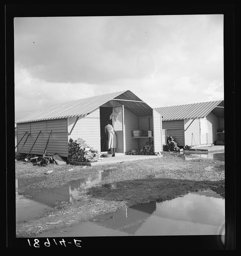 United States government camp for migrants (Farm Security Administration), Farmersville, California. Prefabricated steel dwellings "one step up from a tent" replace the use of tents in the newer California camps