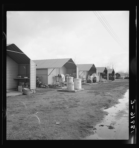 United States government camp for migrants (Farm Security Administration), Farmersville, California. Prefabricated steel dwellings "one step up from a tent" replace the use of tents in the newer California camps