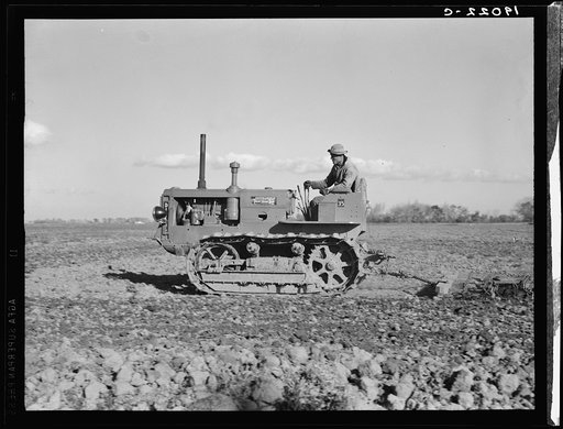 West side of San Joaquin Valley, California. Caterpillar diesel type tractor is common in California. Only very large-scale operations can afford this type. Cultivating potato-fields