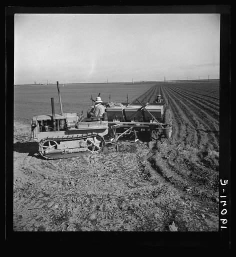 Kern County, California. Large-scale mechanized farming. The potato planter, operated by a crew of three men, makes the rows, fertilizes and plants potatoes in one operation