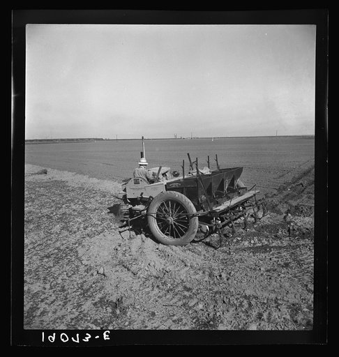 Kern County, California. Large-scale mechanized farming. The potato planter, operated by a crew of three men, makes the rows, fertilizes and plants in one operation