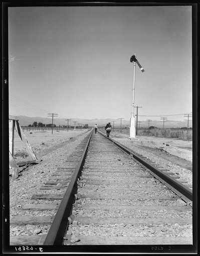 Untitled photo, possibly related to: Looking east down the railroad track, near Calipatria, California. Single men, itinerants with "bindles" waiting for the freight