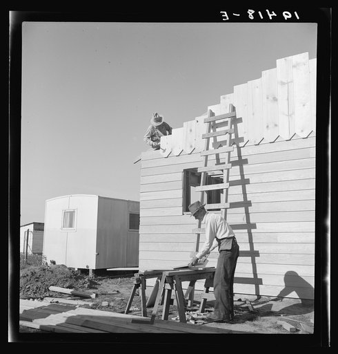 Father and son, recent migrants to California, building house in rapidly growing settlement of lettuce workers on fringe of town. Salinas, California