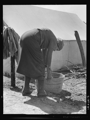 A grandmother washing clothes in a migrant camp. Stanislaus County, California