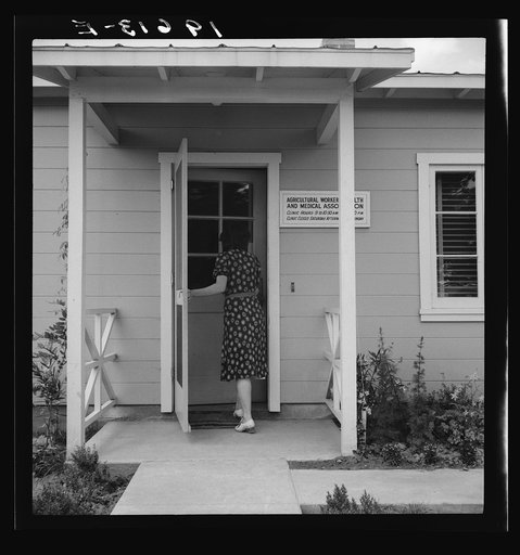 Untitled photo, possibly related to: Tulare County, Farmersville, California. Farm Security Administration (FSA) camp for migratory agricultural workers. Entering clinic of Agricultural Workers' Health and Medical Association (FSA) for nurse's help with sick baby. Older woman says, "I'm just a neigh