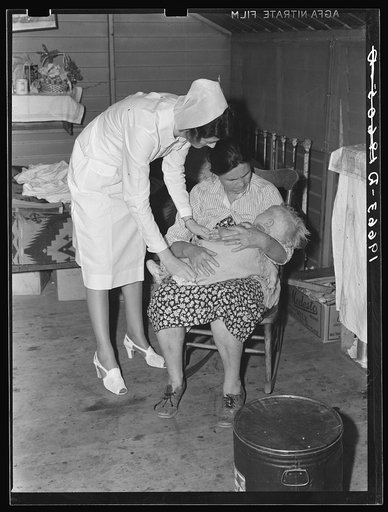 Tulare County, California. Farm Security Administration (FSA) camp for migratory agricultural workers at Farmersville. Nurse of Agricultural Workers' Health and Medical Association (FSA) is assigned to camp. Photo shows her attending sick baby