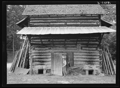 Untitled photo, possibly related to: Tobacco barn. Person County, North Carolina. Piece of sheet iron on the left is used to cover the opening of the furnace when starting the fire