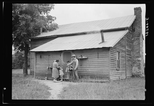 Untitled photo, possibly related to: Tobacco sharecropper and his family at the back of their house showing kitchen door, household equipment, foot path to barn. Person County, North Carolina