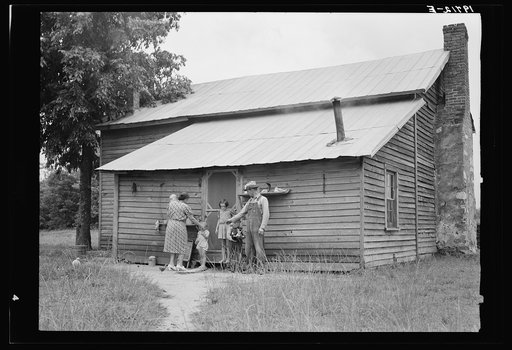 Untitled photo, possibly related to: Tobacco sharecropper and his family at the back of their house showing kitchen door, household equipment, foot path to barn. Person County, North Carolina