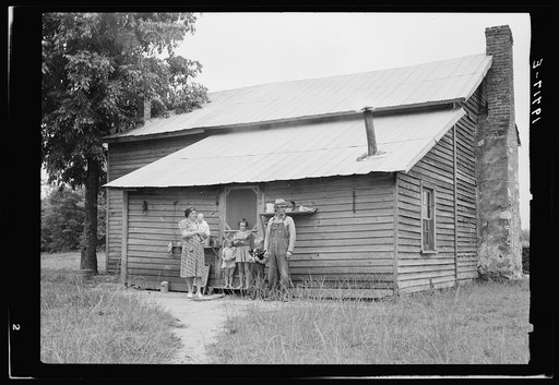 Untitled photo, possibly related to: Tobacco sharecropper and his family at the back of their house showing kitchen door, household equipment, foot path to barn. Person County, North Carolina