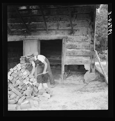 Untitled photo, possibly related to: Putting in new flues in tobacco barn. The fire burns out the bricks and furnaces have to be replaced every ten or fifteen years. Orange County, North Carolina