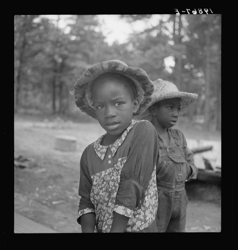 Untitled photo, possibly related to: Grandchildren of tobacco sharecropper down at barns. Note construction of tobacco sleds which have just been repaired by Zollie Lyons. Beyond them the screened platform in which that member of the family sleeps who tends the fire during the night. Wake County, No