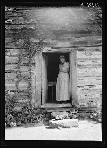 Untitled photo, possibly related to: Caroline Atwater standing in the kitchen doorway of double one and a half story log house. North Carolina