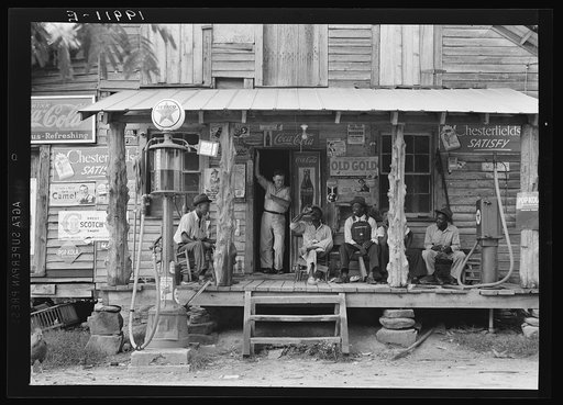 Country store on dirt road. Sunday afternoon. Note the kerosene pump on the right and the gasoline pump on the left. Rough, unfinished timber posts have been used as supports for porch roof.  Negro men are sitting on the porch. Brother of store owner stands in doorway. Gordonton, North Carolina