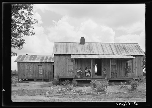 Untitled photo, possibly related to: House of Negro tenant family. This is a larger house than usual box type. Has several rooms, unscreened, but well kept. Part of the family is sitting on the porch resting--Saturday afternoon. The oldest son on the mule is on his way to visit a neighbor. Pittsboro