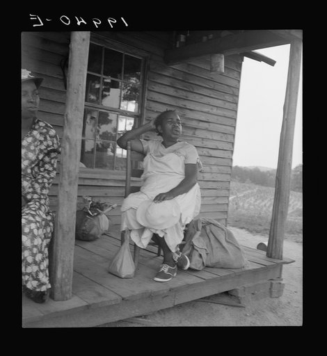 Untitled photo, possibly related to: Mother of sharecropper family and friend coming up the road in the rain, bringing home sacks of vegetables from the neighbor place. Person County, North Carolina. Off Highway 144