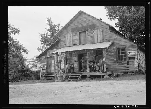 Country store on dirt road, Sunday afternoon. Note kerosene pump on right and gasoline pump on the left. The brother of the owner of the store stands in the doorway. Near Gordenton, North Carolina