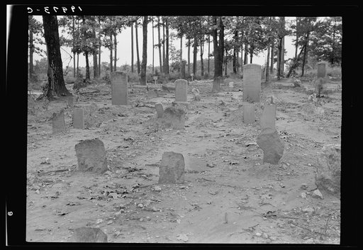 A red clay Negro cemetery. No attempts to lay out crops. The graves are in rows with narrow spaces between. This cemetery was a solid expanse of red clay washed by the rains. Even the gravestones are colored by the red clay beaten against them by rain On such markers as are cut there was misspelling