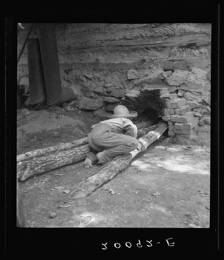 Ten year old son of tobacco tenant tends the fire which is curing the tobacco in the barn. Granville County, North Carolina