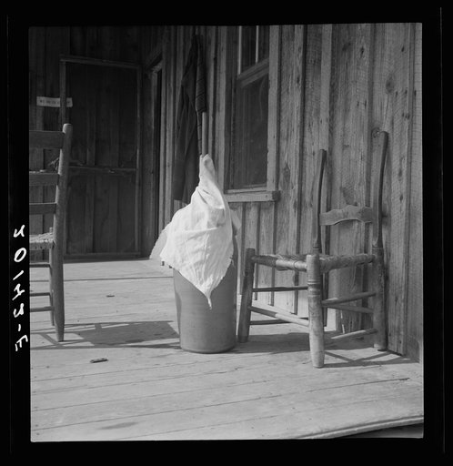 Pottery butter churn on porch of Negro tenant family. The churn is covered with a cloth to keep the flies out. Note chair seat of split white oak. Chair making is a local craft long developed in this region. Randolph County, North Carolina
