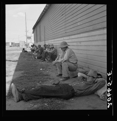 Idle men seated in shade on the other side of Pastime Cafe, three weeks before opening of Klamath Basin potato harvest. California, Siskiyou County, Tulelake. See general caption number 43