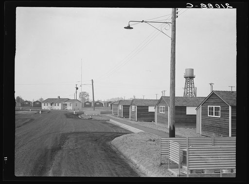 Looking down one street in newly completed camp (FSA - Farm Security Administration). Note garbage disposal, street lights, street curbing, water tank, and manager's house at end of street. Near McMinnville, Yamhill County, Oregon. General caption number 50
