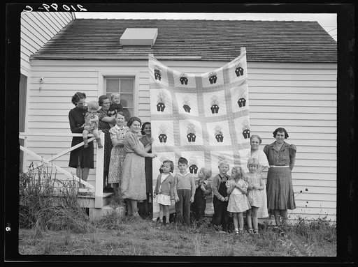 Farm women of the "Helping Hand" club display a pieced quilt which they are making for the benefit of one of their numbers. Near West Carlton, Yamhill County, Oregon. General caption number 58-11