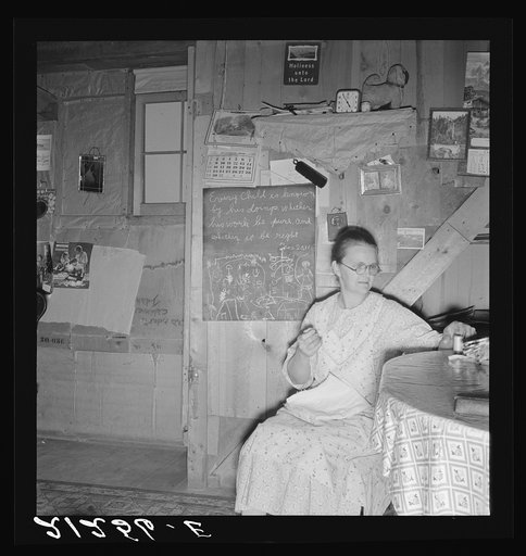 Mrs. Hull in one-room dugout basement home (note blackboard.) "I wanted a blackboard for a long time for my Bible verses, to keep them in our mind. Got it last year." Dead Ox Flat, Malheur County, Oregon. General caption number 67-111