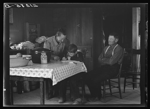 Untitled photo, possibly related to: The Wardlow family in their dugout basement home on Sunday. The youngest boy copies out a recipe for his mother. Dead Ox Flat, Malheur County, Oregon