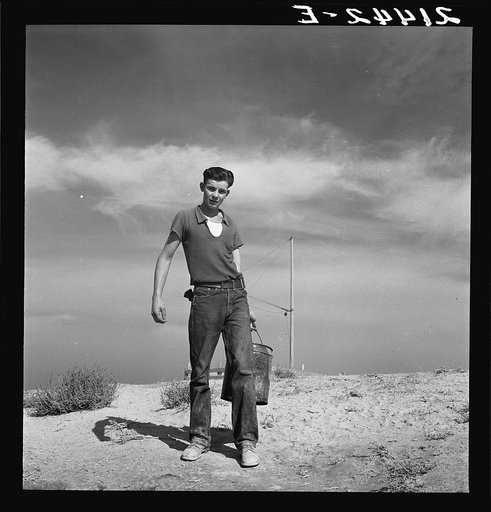 Vale Owyhee irrigation project. Seventeen year old boy going to feed the pigs. Homedale district, Malheur County, Oregon